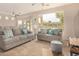 Spacious living room with gray sofas, a coffee table, and large windows at 42493 W Candyland Pl, Maricopa, AZ 85138