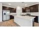 Well-appointed kitchen with stainless steel appliances, island with sink, and dark wood cabinets at 46941 W Old Timer Rd, Maricopa, AZ 85139