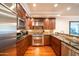 Modern kitchen features stainless steel appliances, dark wood cabinetry, granite countertops, and hardwood floors at 4909 N Woodmere Fairway -- # 2003, Scottsdale, AZ 85251