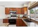 Warm kitchen features wood cabinets, granite countertops, stainless steel appliances, and backyard views at 5102 E Charleston Ave, Scottsdale, AZ 85254