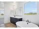 Bathroom features a soaking tub, dark cabinets, and a window with a scenic view at 7662 W Rowel Rd, Peoria, AZ 85383