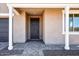 Covered front porch with stone flooring and a sleek front door, framed by white porch columns at 7662 W Rowel Rd, Peoria, AZ 85383