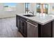 Close up of kitchen island with stainless steel dishwasher, dark cabinets, and view to the backyard at 7662 W Rowel Rd, Peoria, AZ 85383