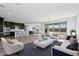 Bright living room featuring neutral furniture, a modern kitchen, and expansive glass doors to backyard views at 7662 W Rowel Rd, Peoria, AZ 85383