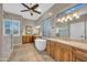 Bright bathroom with a ceiling fan, soaking tub, dual vanity sinks, and tiled glass shower at 12953 W Figueroa Dr, Sun City West, AZ 85375