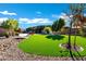 A landscaped backyard features an expanse of green lawn, decorative rocks, and mature trees at 1783 E Desert Broom Pl, Chandler, AZ 85286