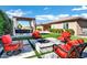 Inviting backyard featuring a fire pit, pergola with seating, lush green grass and red cushioned chairs at 1783 E Desert Broom Pl, Chandler, AZ 85286