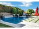 A luxurious pool featuring a rock waterfall is surrounded by green hedges, providing a serene and private oasis at 1783 E Desert Broom Pl, Chandler, AZ 85286