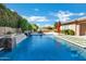 A sparkling pool features a waterfall and is surrounded by lush landscaping, stone pavers, and a dining set at 1783 E Desert Broom Pl, Chandler, AZ 85286