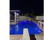 Blue-lit swimming pool at night with diving board and waterfall at 3957 E Expedition Way, Phoenix, AZ 85050