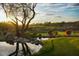 Scenic view of a golf course with a pond, lush greenery, and a tree silhouette at sunset at 41007 N Harbour Town Way, Anthem, AZ 85086
