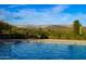 Sparkling blue pool with lounge chairs in the background and desert landscaping with the outline of mountains in the distance at 41007 N Harbour Town Way, Anthem, AZ 85086