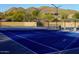 Well-maintained blue tennis court with mountain views and surrounding lush greenery at 41007 N Harbour Town Way, Anthem, AZ 85086