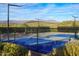 Modern blue tennis court with mountain views in the background and desert landscaping, surrounded by a black chain link fence at 41007 N Harbour Town Way, Anthem, AZ 85086