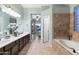 Spa-like bathroom with double vanity, large soaking tub, and view to bedroom at 4516 E Madre Del Oro Dr, Cave Creek, AZ 85331