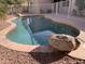 Relaxing kidney-shaped pool surrounded by rocks and a fenced backyard at 8014 E Plata Ave, Mesa, AZ 85212