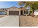 Charming single-story home with brown garage and desert landscaping at 10826 W Woodland Ave, Avondale, AZ 85323