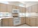 Well-lit kitchen featuring light wood cabinets, white appliances, and tile countertops at 13811 W Via Tercero --, Sun City West, AZ 85375