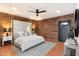 Main bedroom with brick wall, king bed, and access to backyard at 3807 N 55Th Pl, Phoenix, AZ 85018