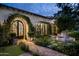 Elegant home exterior with arched entryway, lush landscaping, and stone pathway at 7305 E Royal Palm Rd, Scottsdale, AZ 85258