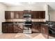 Modern kitchen with dark brown cabinets, granite countertops, and stainless steel appliances at 832 E Stottler Dr, Gilbert, AZ 85296