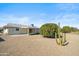 View of the home's back exterior, featuring a gravel yard, cactus, and citrus trees at 19619 N Signal Butte Cir, Sun City, AZ 85373