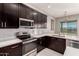 Modern kitchen with dark cabinetry, quartz countertops, and stainless steel appliances at 24421 W Morning Vista Ln, Wittmann, AZ 85361