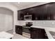 Modern kitchen with dark cabinetry, quartz countertops, and stainless steel appliances at 24421 W Morning Vista Ln, Wittmann, AZ 85361