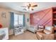 Bedroom with crib, accent wall, and comfortable chair at 4333 W Shaw Butte Dr, Glendale, AZ 85304