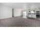 Spacious living room with grey carpet adjacent to a modern kitchen with wood-look flooring at 7710 S 350Th Ave, Tonopah, AZ 85354