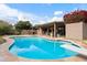 Inviting kidney-shaped pool with diving board, surrounded by a patio and lush landscaping at 9041 E Ludlow Dr, Scottsdale, AZ 85260