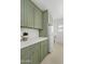 Modern laundry room with green cabinets and white appliances at 9449 S 156Th Pl, Gilbert, AZ 85234