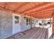 Covered patio with wooden beams, table and chairs, and access to the home at 10137 N White Rd, Maricopa, AZ 85139