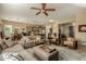 Open-concept living room with a ceiling fan, tile floors, and a view into the kitchen and dining area at 17833 W Verdin Rd, Goodyear, AZ 85338