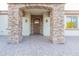 Charming front entrance with a stone archway, sconce lighting, and paver walkway at 18206 W Solano Ct, Litchfield Park, AZ 85340