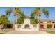 Inviting backyard featuring a stucco fireplace, palm trees, lush landscaping, and a paved patio for outdoor entertaining at 3412 E Indigo Cir, Mesa, AZ 85213