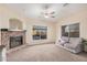 Living room with a fireplace, large windows, and a ceiling fan at 14836 W Desert Hills Dr, Surprise, AZ 85379