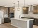 Modern kitchen boasts stainless steel appliances, island with pendant lights, and chevron backsplash at 17761 W Elm St, Goodyear, AZ 85395