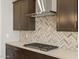 Close-up of kitchen featuring stainless steel hood, chevron backsplash, gas cooktop, and gray cabinets at 17761 W Elm St, Goodyear, AZ 85395