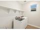 Convenient laundry room featuring a modern washer and dryer with overhead shelving at 17761 W Elm St, Goodyear, AZ 85395