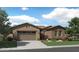 One-story home with a two-toned brick exterior, three-car garage, and landscaped front yard at 23083 E Lords Way, Queen Creek, AZ 85142