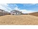 A spacious, dirt-covered backyard featuring a white home and a tall block wall fence for added privacy at 2316 W Moody Trl, Phoenix, AZ 85041