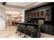 Stylish home bar with dark cabinetry, granite countertop and industrial barstools at 23414 N 84Th Pl, Scottsdale, AZ 85255