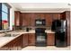 Modern kitchen with dark wood cabinets, black appliances, and tile backsplash at 23414 N 84Th Pl, Scottsdale, AZ 85255