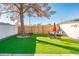 Backyard with artificial turf, patio furniture, and a large tree providing shade at 10902 W Flanagan St, Avondale, AZ 85323