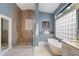 Modern bathroom with a walk-in shower, soaking tub, and a stylish glass block window at 11748 N 80Th Pl, Scottsdale, AZ 85260