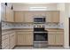 Stainless steel appliances and light wood cabinets in this kitchen at 15665 W Azalea Ln, Surprise, AZ 85374