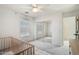 Bedroom with ceiling fan, window, gray carpet, wooden crib, and a mirrored closet at 18260 W Bridger St, Surprise, AZ 85388