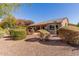 Home's backyard with covered patio, gravel landscaping, and mature shrubs at 20652 N Wishing Well Ln, Maricopa, AZ 85138