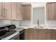 Modern laundry room featuring wood cabinets, granite countertops, a stainless steel sink, and new appliances at 37178 N Winding Wash Trl, Carefree, AZ 85377